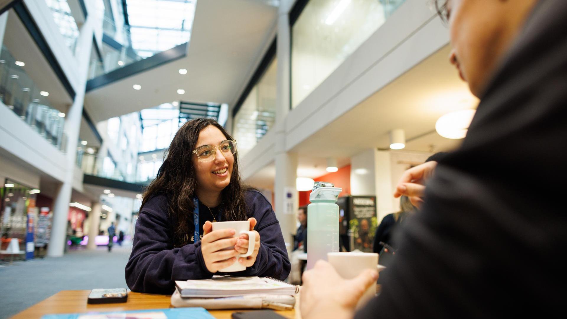 Female student talking with cup of tea Augustine House Canterbury